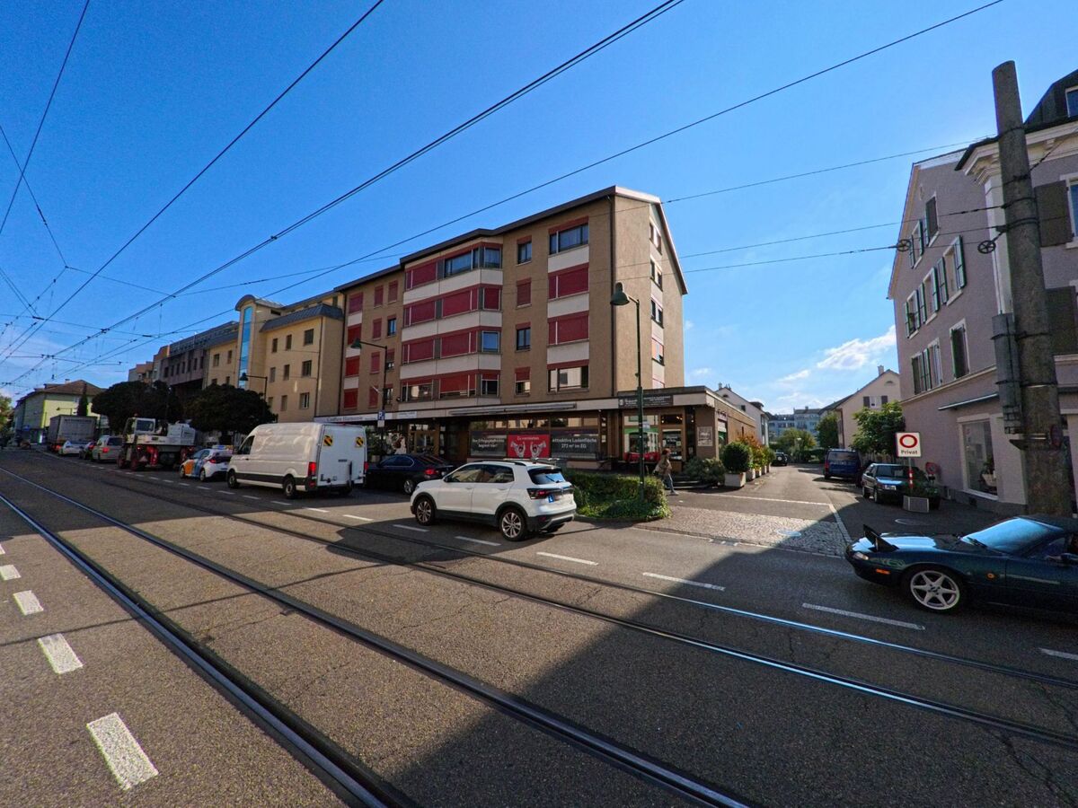 Zwischen Tramgleisen und Wohnhaeusern in Birsfelden (4127, Kanton Basel-Landschaft) oeffnet sich eine kleine Seitengasse mit Gastronomie und parkenden Fahrzeugen.