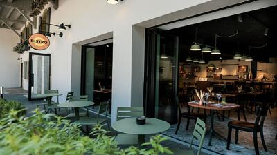Das Bistro du Moulin de Sévery in Sévery (1141, Kanton Waadt) bietet eine gemütliche Terrasse mit grünen Tischen und einen modernen Innenbereich mit stilvoller Beleuchtung.