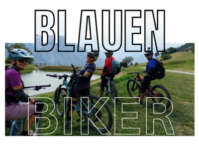 In Ettingen (4107, Kanton Basel-Landschaft) pausieren mehrere Mountainbiker am Seeufer und blicken mit ihren Velos auf die umliegende Landschaft.