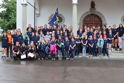 Die Mitglieder des Blaurings Steinhausen (6312, Kanton Zug) stehen in einheitlichen T-Shirts vor einem Gebäude und posieren gemeinsam für ein Gruppenfoto.