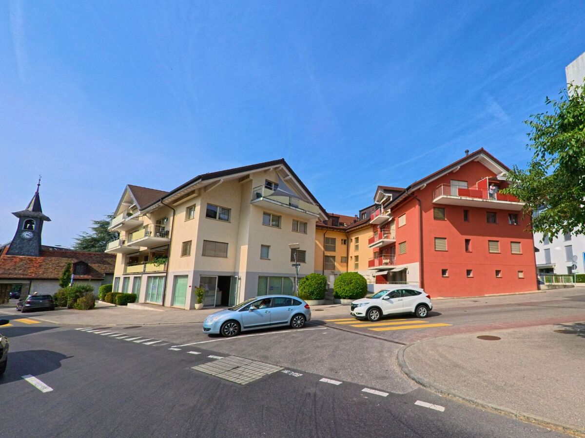 In Blonay_-_Saint-Legier (1807, Kanton Waadt) stehen moderne Mehrfamilienhaeuser mit Balkonen, neben denen der Turm einer kleinen Kirche sichtbar ist.