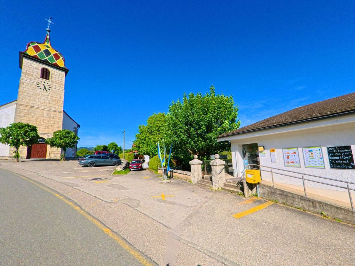 In Boécourt (2856, Kanton Jura) ist der Uhrenturm der Kirche mit einem bunten Dach und ein Postgebäude mit einem Schalter zu sehen.