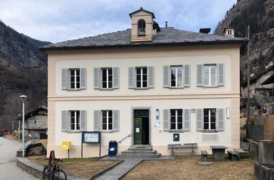 Das Gebäude der Bottega Bistro in Cauco (6546, Kanton Graubünden) steht mit hellen Fensterläden und einer kleinen Treppe am Eingang im Bergtal.