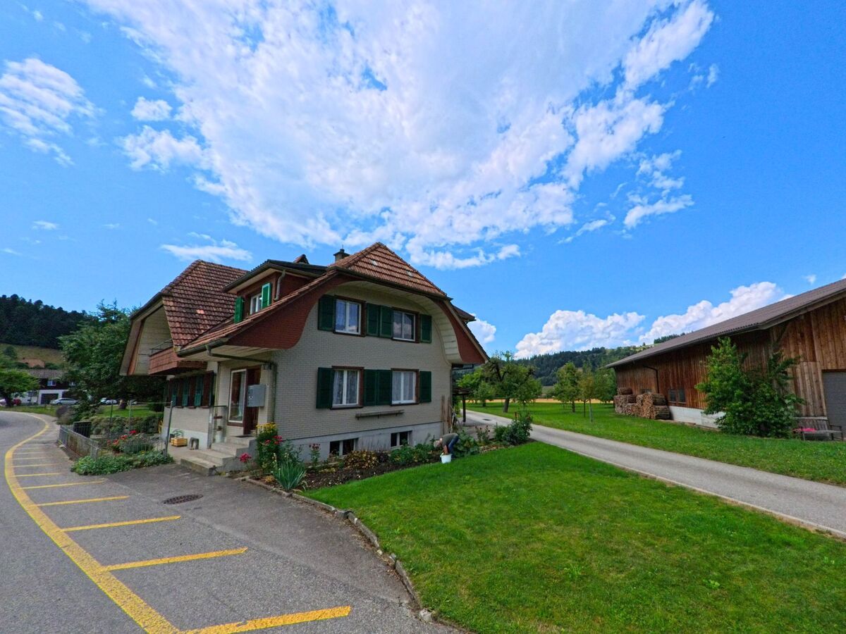 Ein gepflegtes Wohnhaus mit gruenen Fensterlaeden steht in Bowil (PLZ 3533, Kanton Bern) an einer ruhigen Nebenstrasse mit angrenzender Scheune und Garten.