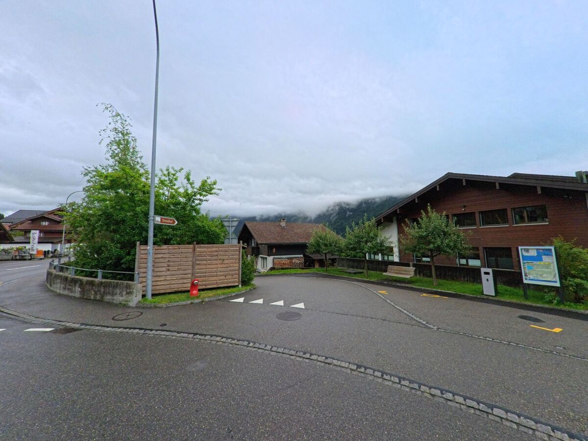 In Brienz (3855, Kanton Bern) liegt ein flach gebautes Gemeindehaus mit Infotafel an einer ruhigen Seitenstrasse, eingerahmt von Wohnhäusern und Obstbäumen.