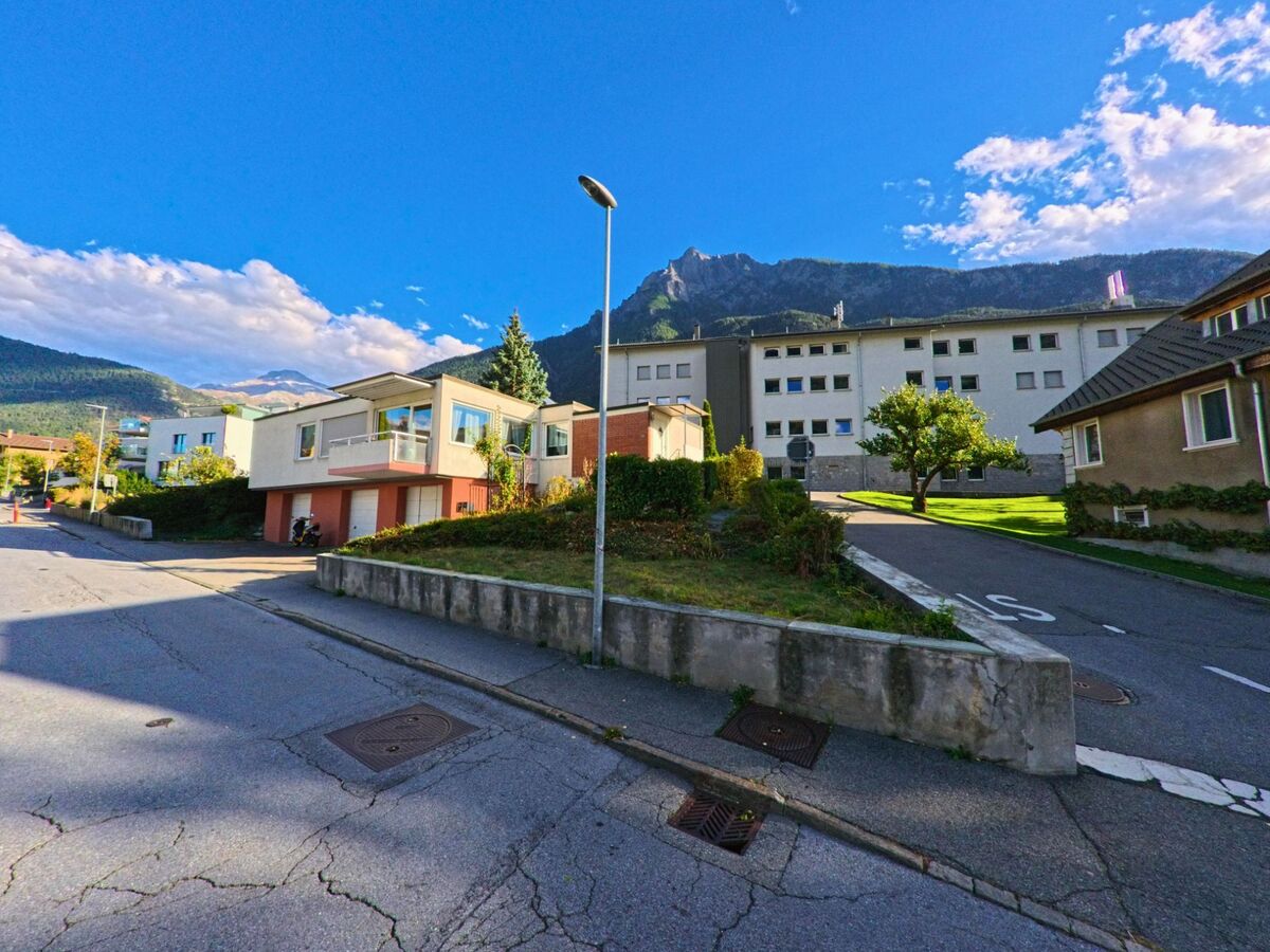 In Brig-Glis (3902, Kanton Wallis) stehen moderne Wohnhaeuser mit gepflegten Gaerten vor der Kulisse der nahen Berge.