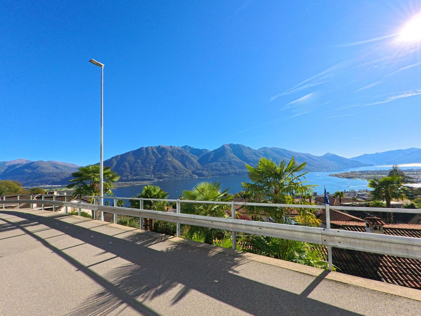 Von einer Strasse in Brione sopra Minusio (6645, Kanton Tessin) eröffnet sich ein weiter Blick über den Lago Maggiore und die umliegenden Berge.