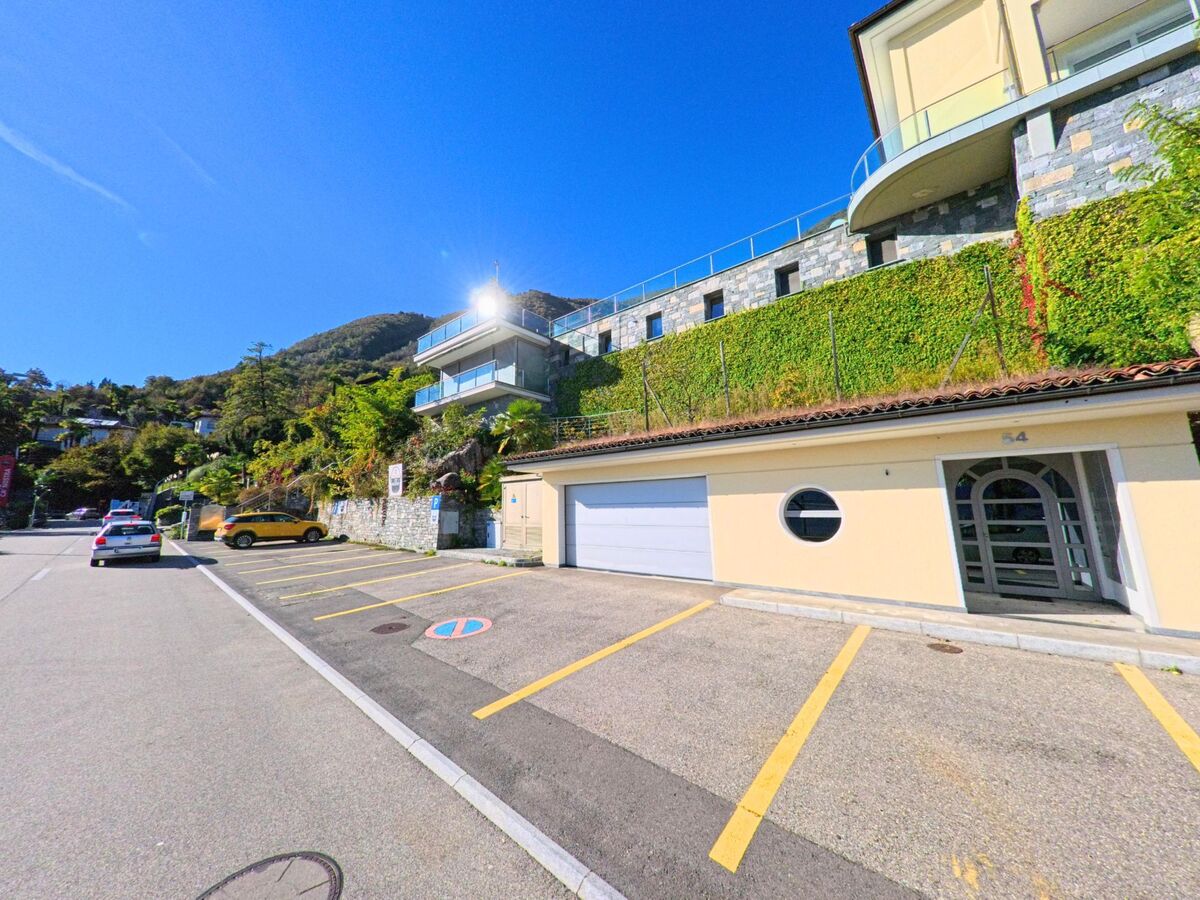 Moderne Wohnhäuser mit Terrassen und Garagen prägen die Hanglage in Brione sopra Minusio (6645, Kanton Tessin) unter klarem Himmel.