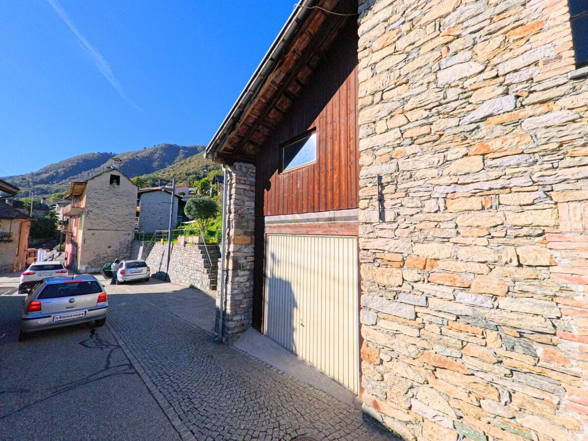 In einer schmalen Gasse von Brione sopra Minusio (6645, Kanton Tessin) reihen sich Steinhäuser mit Holzelementen aneinander.
