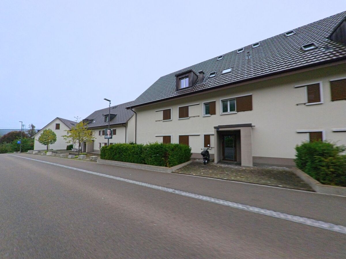 Mehrfamilienhäuser mit hellen Fassaden und geschlossenen Fensterläden reihen sich in Brunegg (5505, Kanton Aargau) entlang einer ruhigen Strasse.