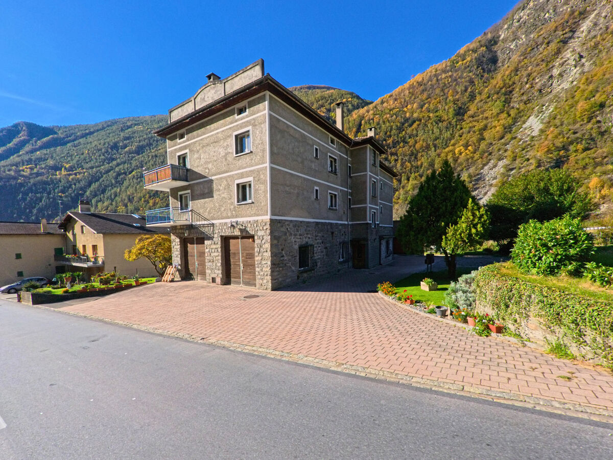Ein massives Wohnhaus mit Steinmauer befindet sich in Brusio, 7743, im Kanton Graubünden an einer ruhig gepflasterten Flaeche.
