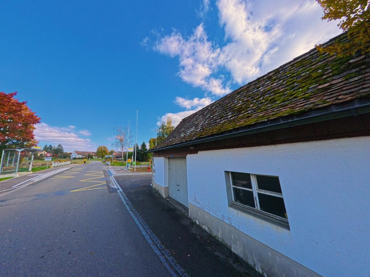 Ein niedriges Gebäude steht nahe einer Bushaltestelle an der Durchgangsstrasse von Buch (8263, Kanton Schaffhausen).