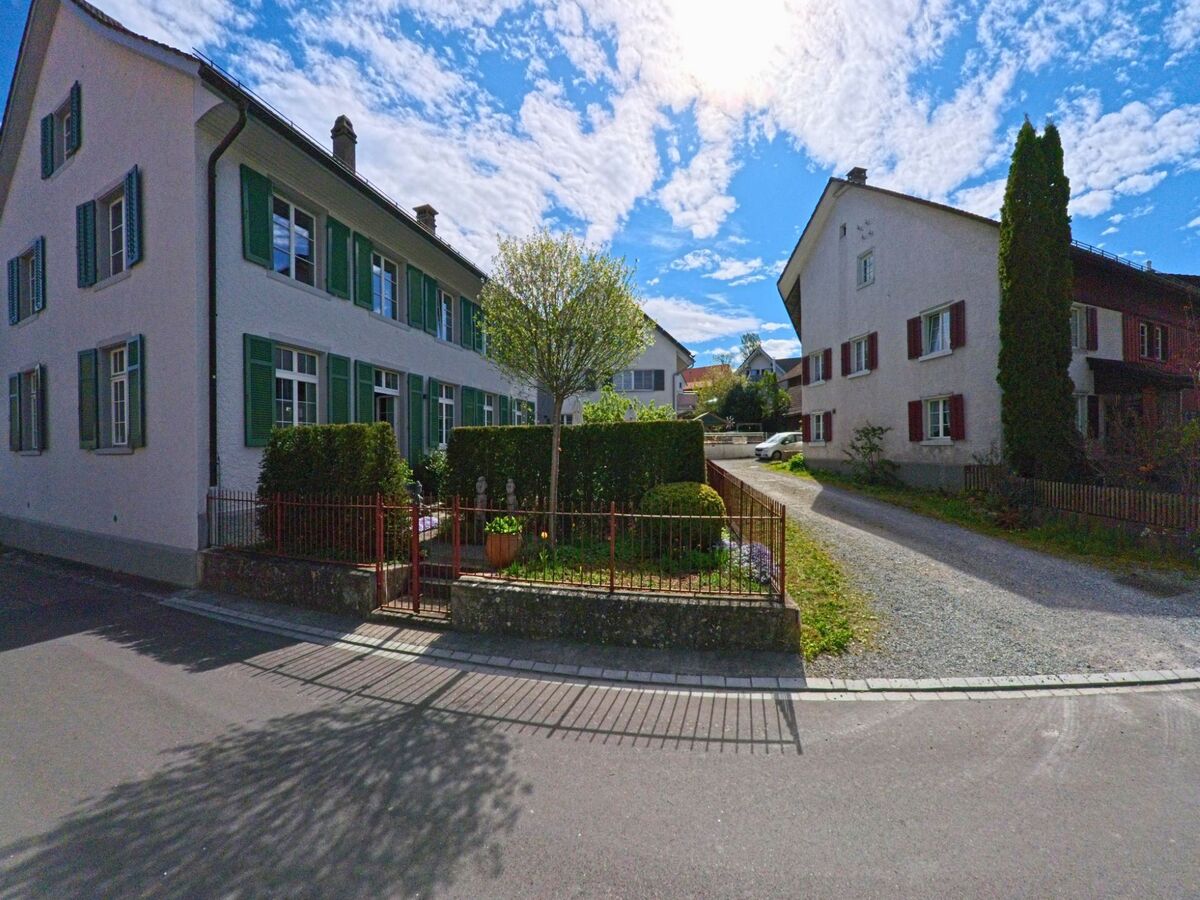 Zwei gepflegte Wohnhäuser mit Fensterläden und Vorgärten stehen in einer ruhigen Seitenstrasse in Buch am Irchel, 8414 im Kanton Zürich.