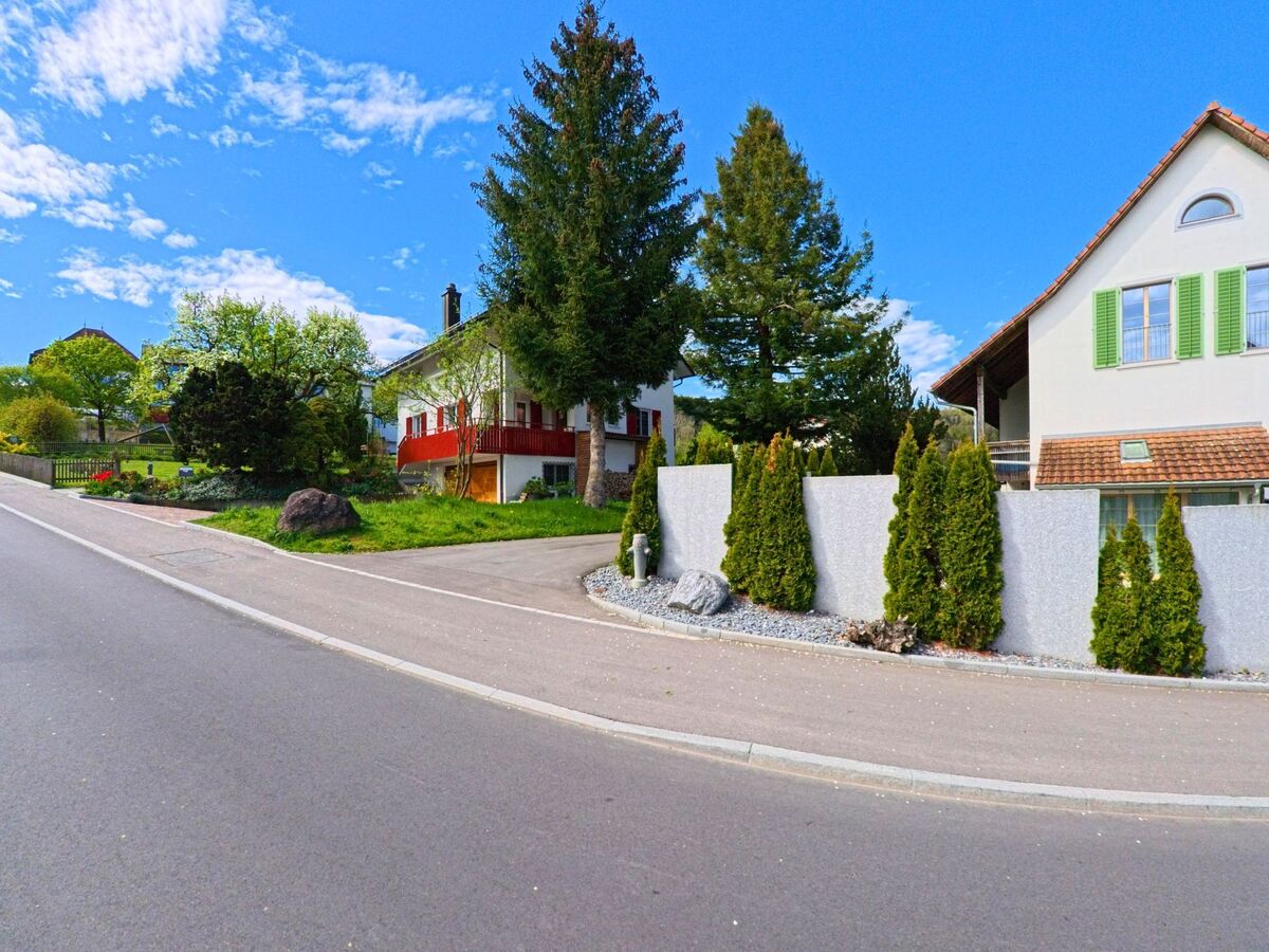 In Buch am Irchel, 8414 im Kanton Zürich säumen Einfamilienhäuser mit gepflegten Gärten und immergrüner Bepflanzung eine ansteigende Wohnstrasse.