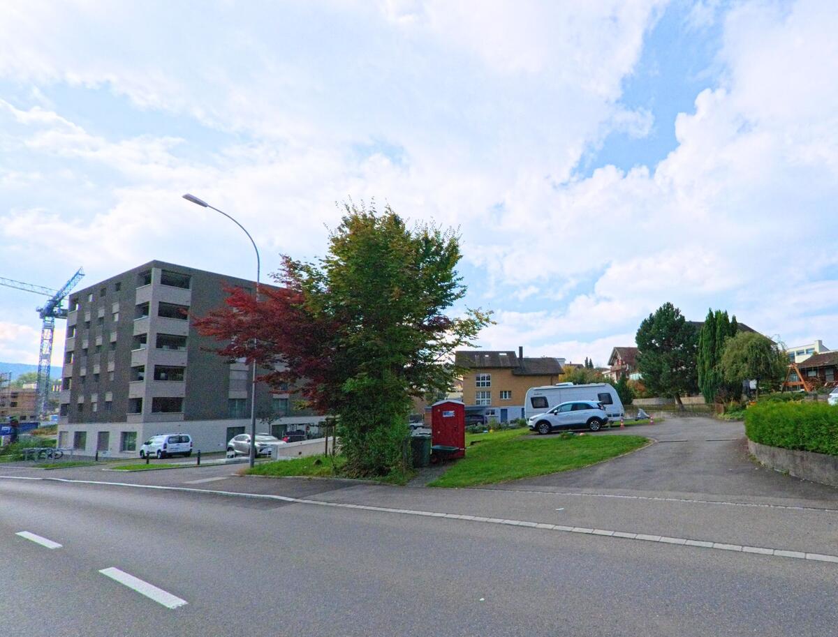 In Buchrain (6033, Kanton Luzern) stehen moderne und sanierte Wohnhaeuser nebeneinander, umgeben von Baukraenen und Parkflaechen.