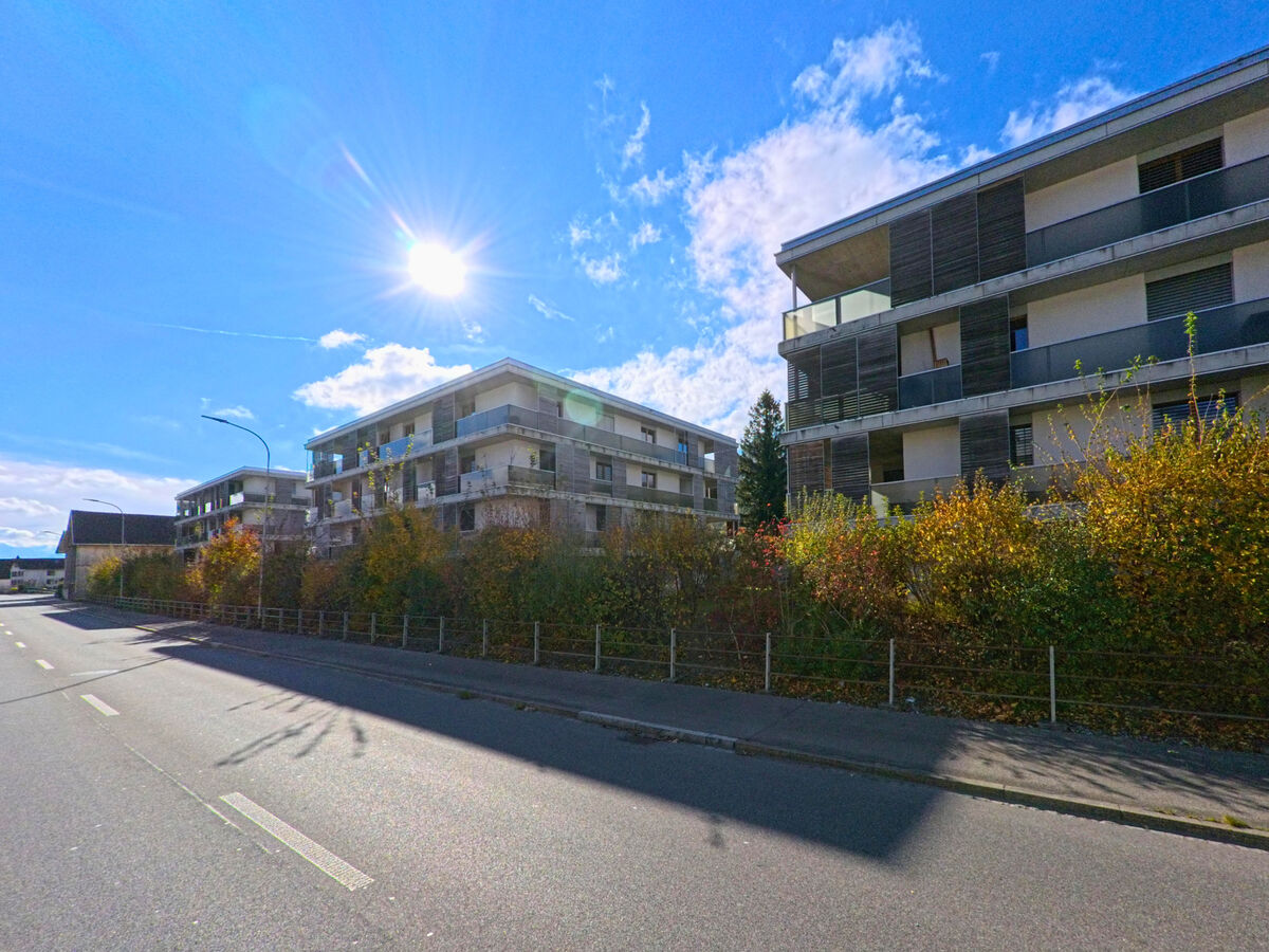 Eine moderne Wohnanlage mit Balkonen steht an einer sonnigen Strasse in Buchs (9470, Kanton St. Gallen).