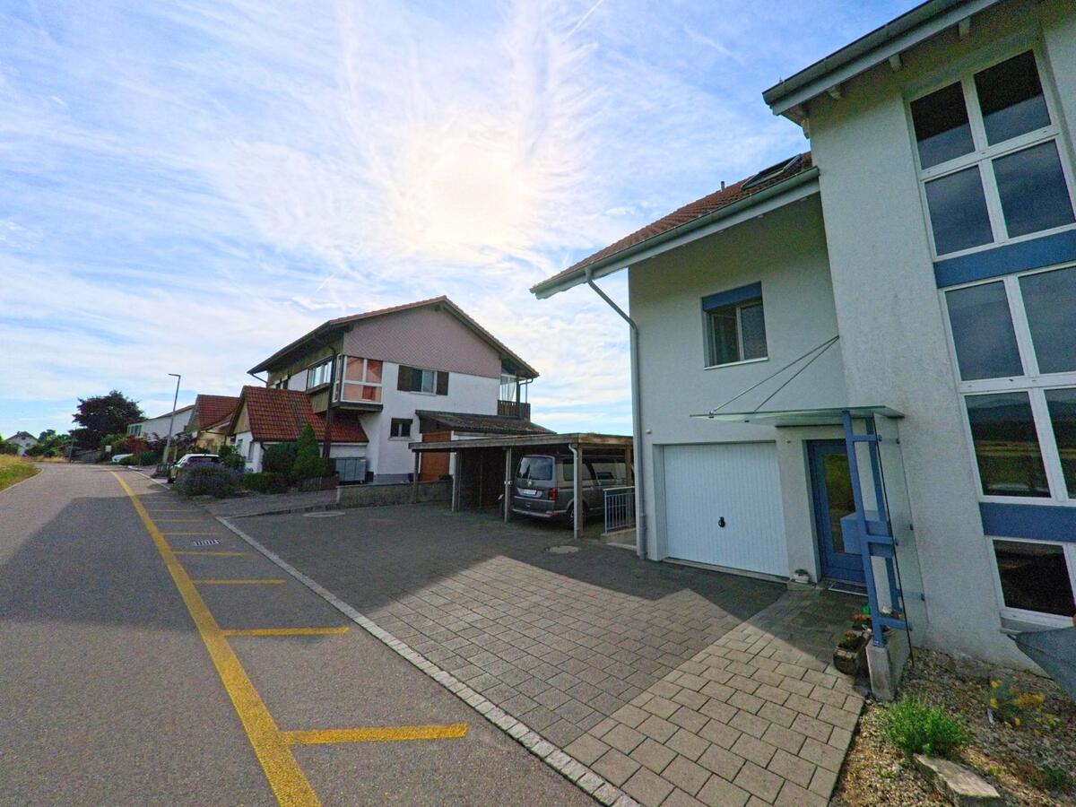 In Bühl (3274, Kanton Bern) reihen sich moderne Einfamilienhäuser mit Vorplätzen und Garagen entlang einer ruhig gelegenen Quartierstrasse.