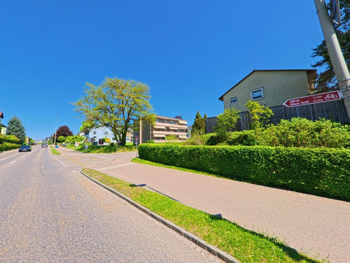  In Bülach im Kanton Zürich (PLZ 8180) verläuft ein Rad- und Fussweg parallel zur Hauptstrasse mit Wegweiser Richtung Bülach Stadt und Eglisau.