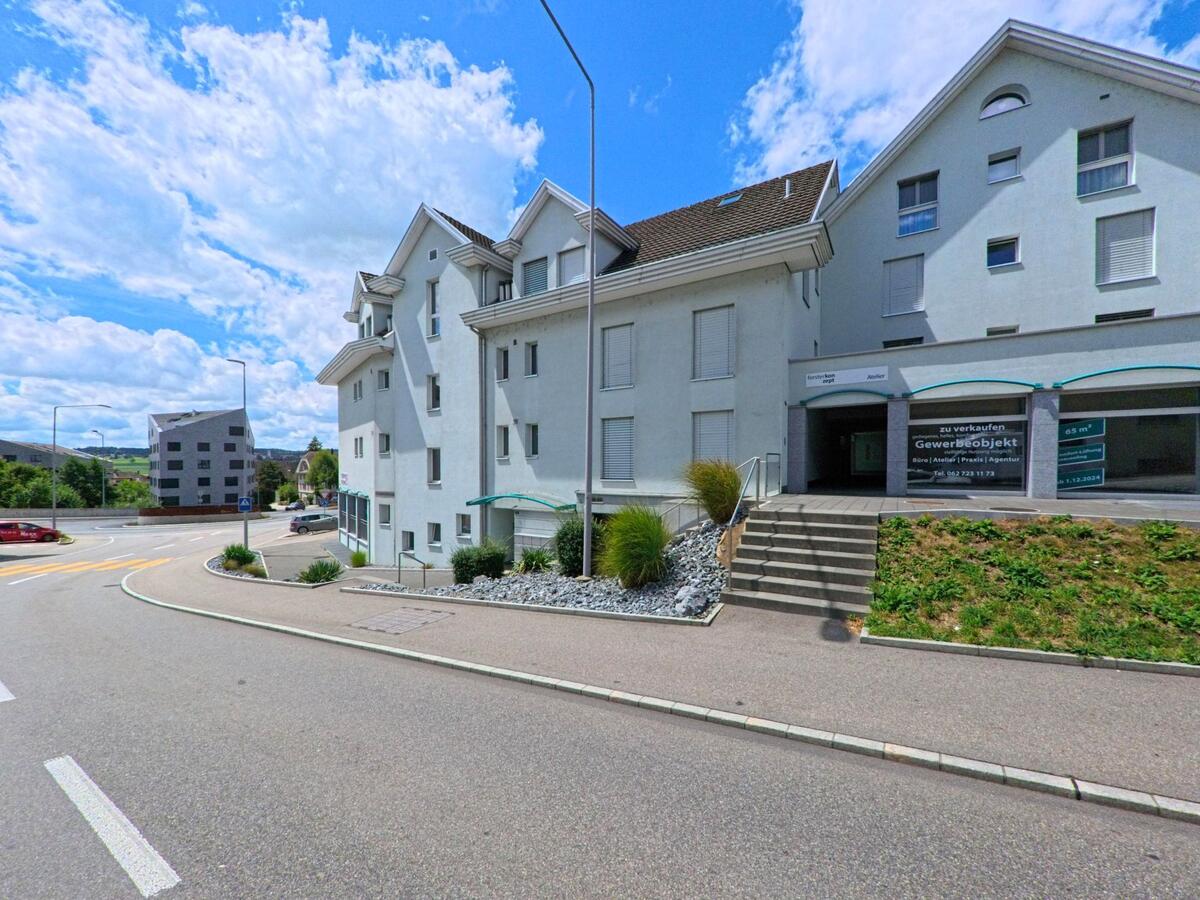 In Bueron (6233, Kanton Luzern) befindet sich ein helles Gebaeude mit einem zum Verkauf ausgeschriebenen Gewerbeobjekt an einer leicht abfallenden Strasse nahe dem Ortseingang.