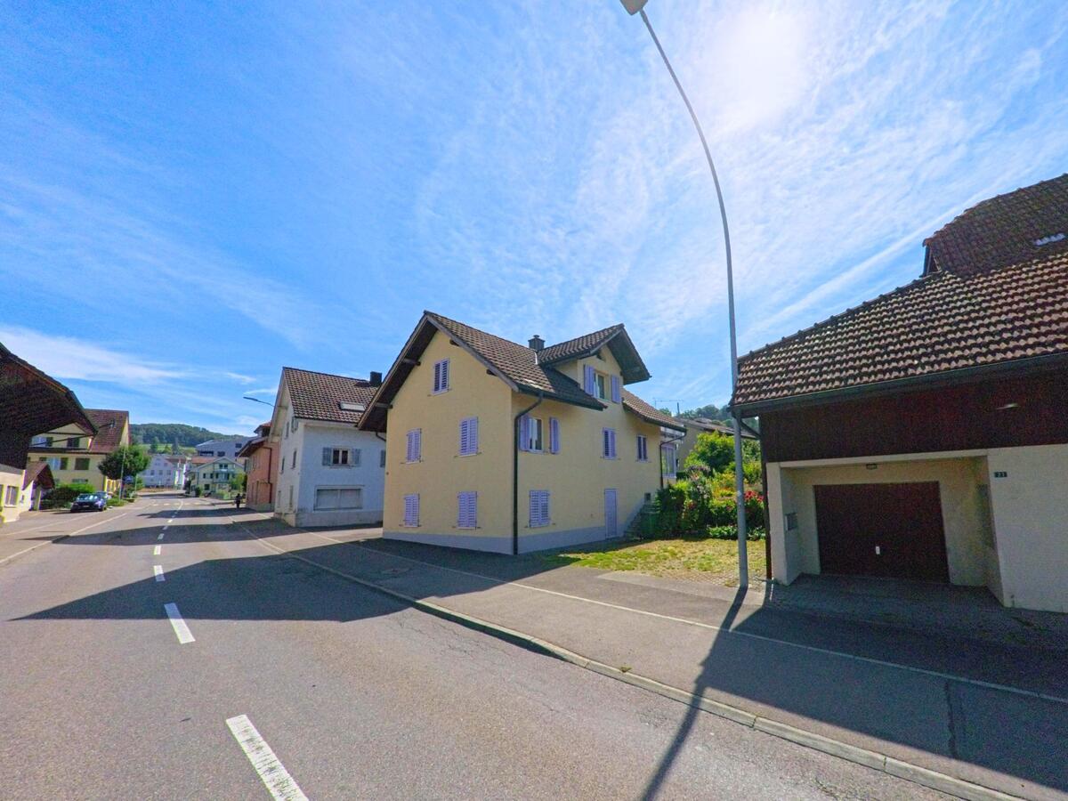 In einer ruhigen Seitenstrasse von Bueron (6233, Kanton Luzern) stehen mehrere traditionelle Wohnhaeuser mit farbigen Fassaden und Fensterlaeden.