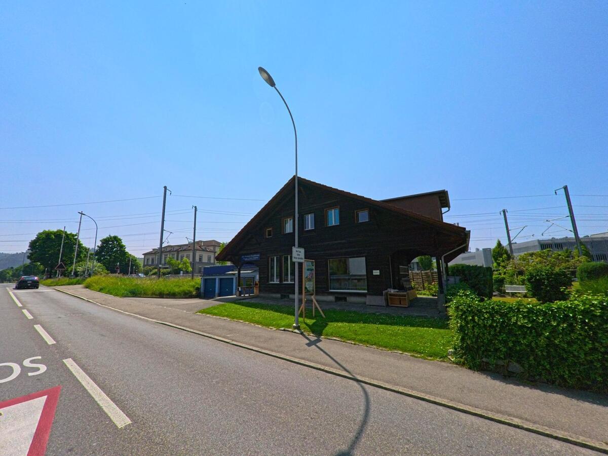 Ein traditionelles Holzhaus steht in Burgdorf (3400, Kanton Bern) an einer Strasse nahe der Bahnlinie, umgeben von gepflegtem Grün.