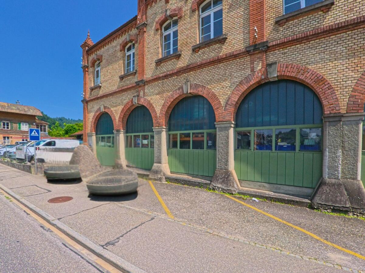 In Burgdorf (3401, Kanton Bern) steht ein altes Fabrikgebäude mit markanten Rundbögen aus Backstein direkt an einer schmalen Quartierstrasse.