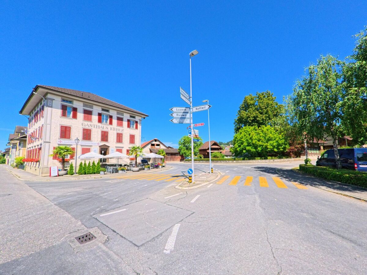 In Buttisholz (6018, Kanton Luzern) markiert das Gasthaus Kreuz mit Aussenterrasse eine zentrale Kreuzung mit Wegweisern in Richtung Luzern, Ruswil und Rotewil.