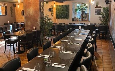 Das Restaurant Castello Grandson in Grandson (1422, Kanton Waadt) zeigt einen gemütlich eingerichteten Speisesaal mit gedeckten Tischen und warmer Beleuchtung.