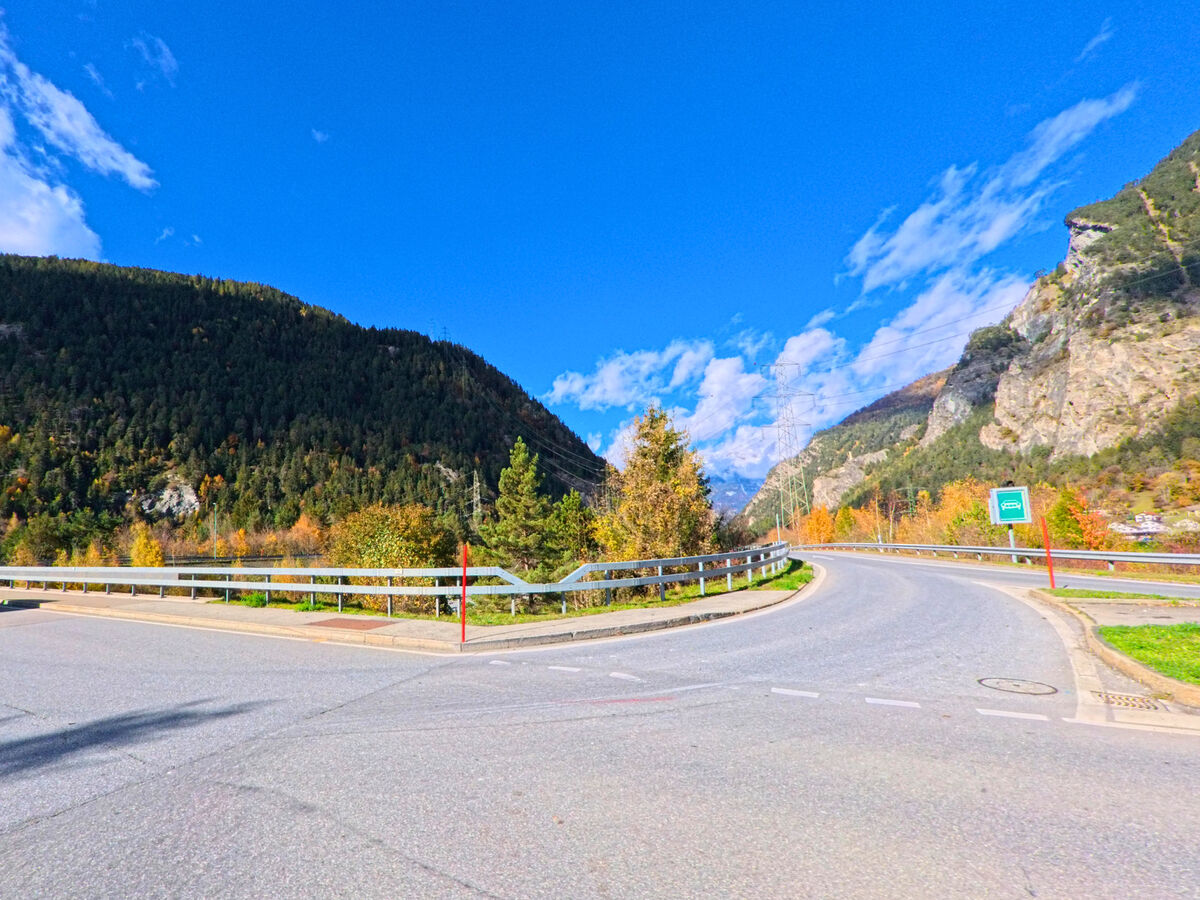 Eine breite Strassenkurve mit Leitplanke fuehrt durch das Tal nahe Cazis (7405, Kanton Graubünden).