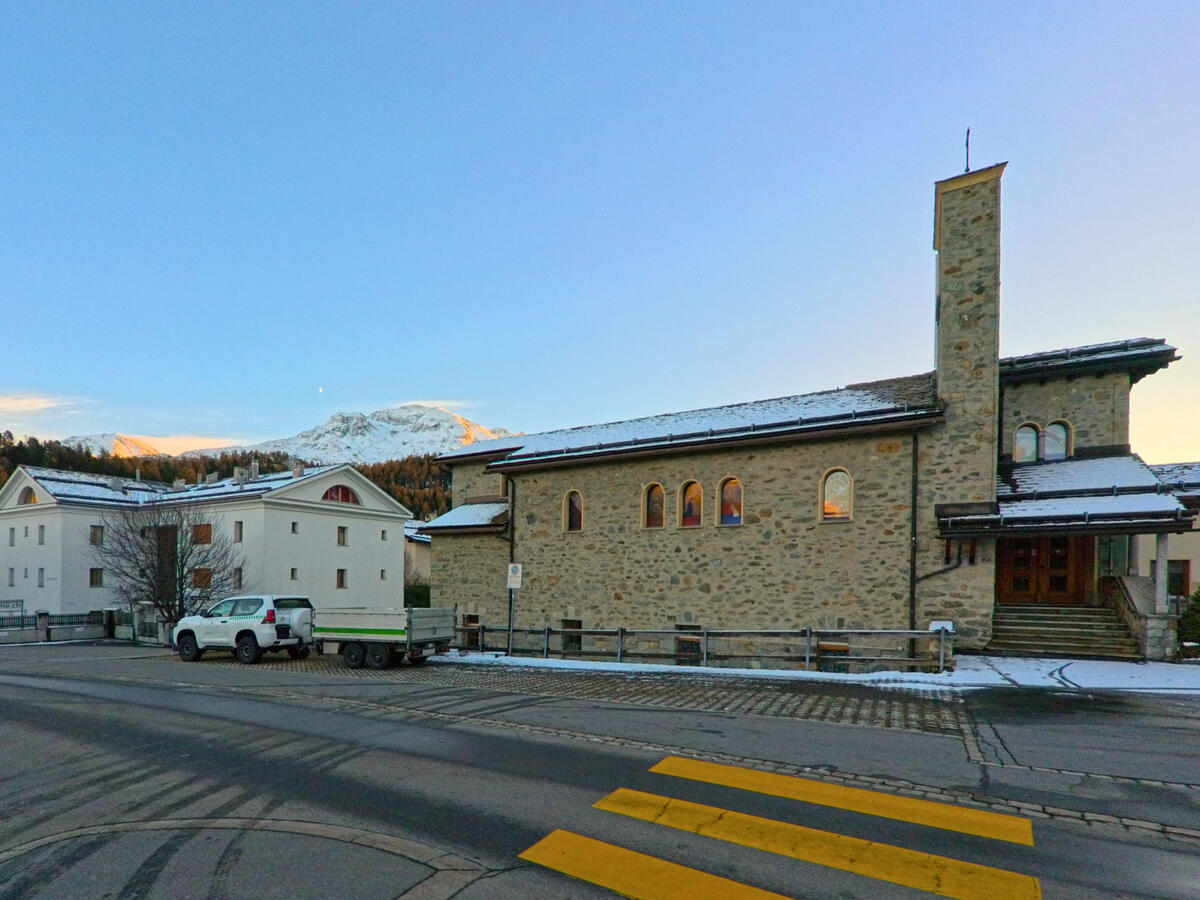 Die Kirche mit markantem Turm liegt an einer Kreuzung im Ortskern von Celerina/Schlarigna (7502, Kanton Graubünden).