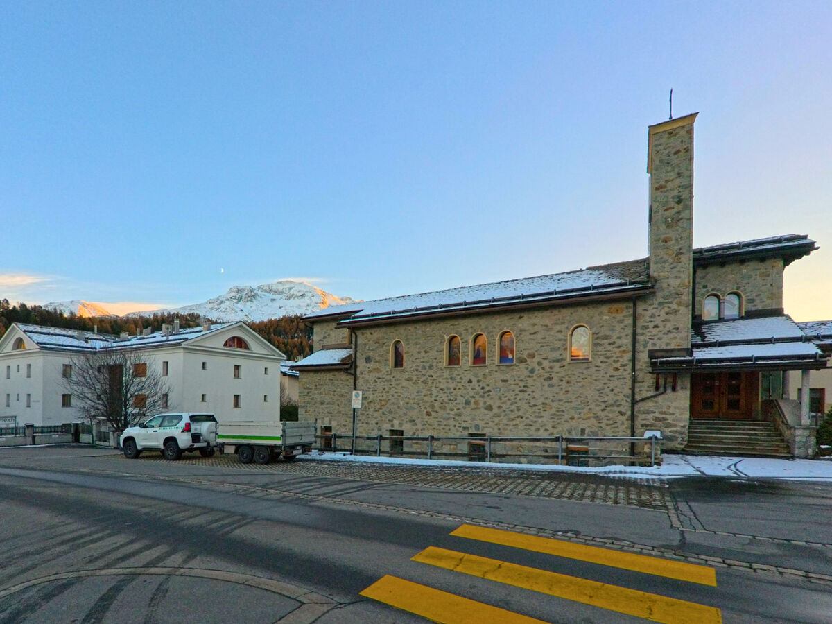 Die Kirche mit markantem Turm liegt an einer Kreuzung im Ortskern von Celerina/Schlarigna (7502, Kanton Graubünden).