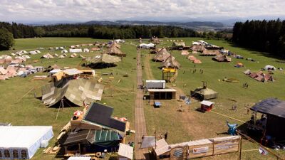 In Seuzach (8472, Kanton Zuerich) liegt ein grossflaechiges Cevi-Lager mit zahlreichen Zelten und Holzbauten auf einer Wiese, waehrend sich Wege durch das weitlaeufige Gelaende ziehen.