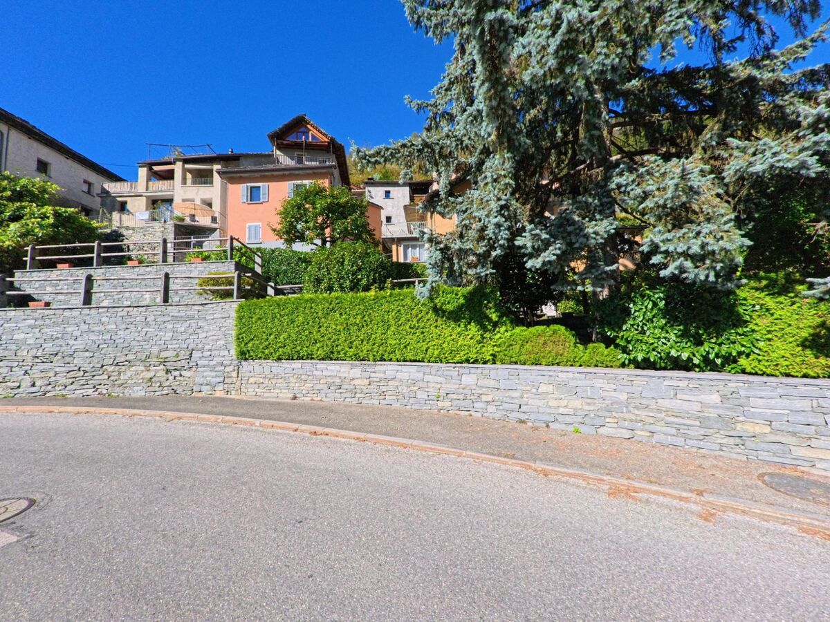 In Cevio (6675, Kanton Tessin) stehen bunte Wohnhäuser auf terrassierten Steinmauern, umgeben von gepflegten Gärten und grossen Bäumen.