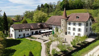 Das Château Salavaux in Salavaux (1585, Kanton Waadt) praesentiere sich als historische Anlage mit rundem Turm, Innenhof und gepflegtem Garten inmitten gruener Huegel.