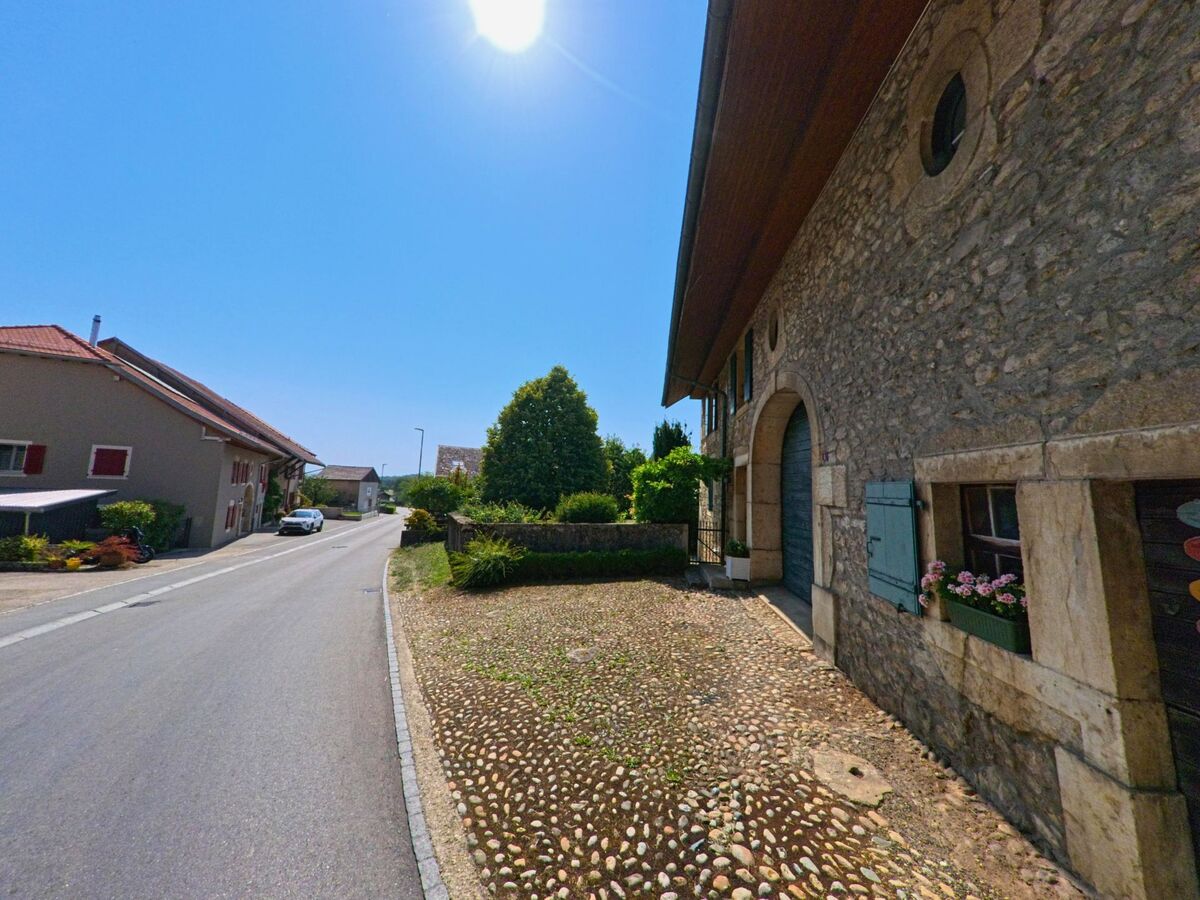 In Chavannes-le-Veyron (1148, Kanton Waadt) verlaeuft eine ruhige Strasse vorbei an alten Steinhaeusern mit blauen Fensterlaeden und gepflegten Vorgartenanlagen.