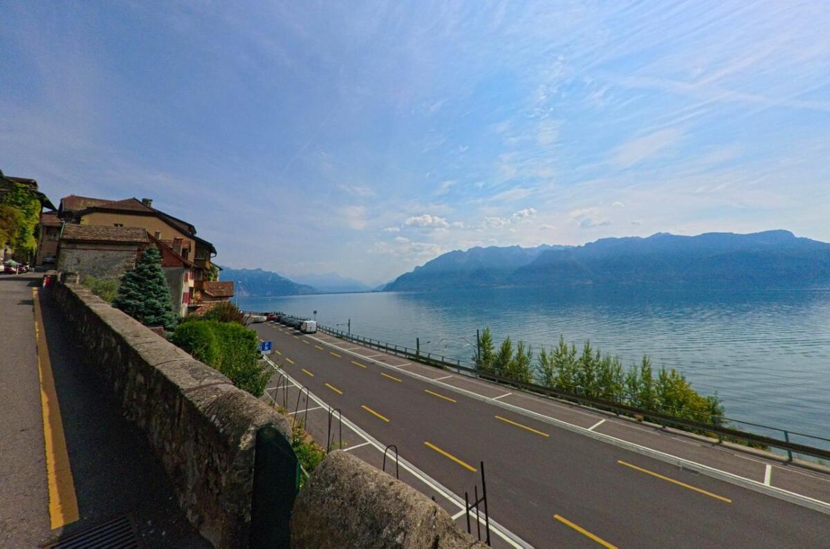 Am Ufer des Genfersees in Chexbres (1071, Kanton Waadt) verläuft eine ruhige Strasse entlang der Wasserlinie mit Blick auf die gegenüberliegenden Alpen.