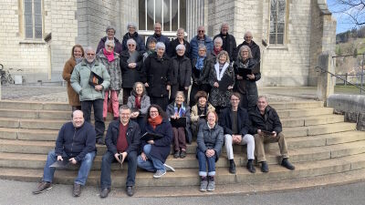 Eine Gruppe von Saengerinnen und Saengern posiert auf den Stufen vor einem Kirchengebaeude in St. Gallen (9000, Kanton St. Gallen) fuer ein gemeinsames Foto.