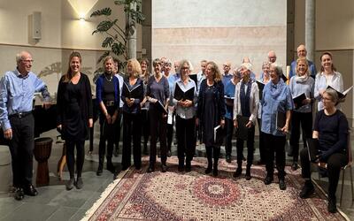 Mitglieder des Chors stehen in Bubikon 8608 im Kanton Zurich gemeinsam in einem Kirchenraum fuer einen musikalischen Auftritt mit Notenmappen bereit.