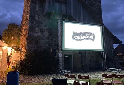Eine Open-Air-Kinovorführung mit Leinwand vor einem historischen Gebäude in Halten, 4566, Kanton Solothurn.