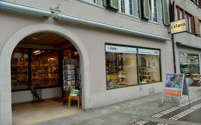 Die Aussenansicht eines Ladens in Sissach (4450, Kanton Baselland) zeigt einen Eingangsbereich mit Schaufenstern, Beschriftung und Warenpraesentation entlang des Gehwegs.