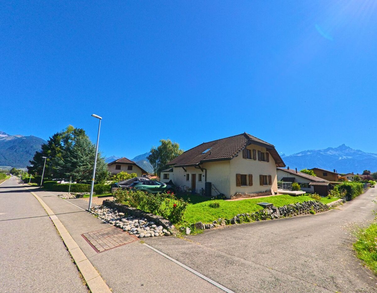 Ein Einfamilienhaus mit Garten liegt in Collombey-Muraz (1893, Kanton Wallis) an einer ruhigen Wohnstrasse mit Blick auf die umliegenden Berge.
