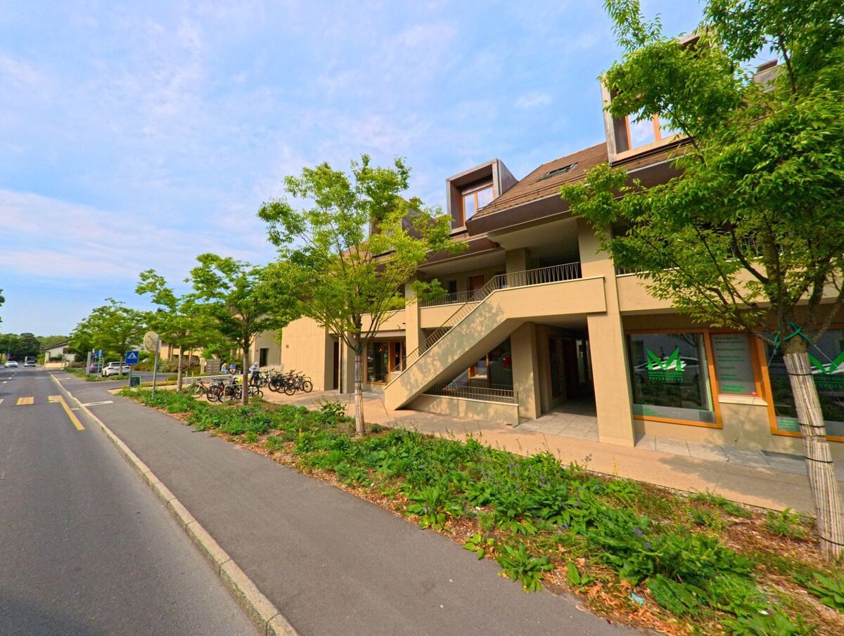 Ein modernes Gebaeude mit grossen Fenstern und einer Aussentreppe steht an einer Strasse in Collonge-Bellerive (1222, Kanton Genf), vor dem Fahrradstaender aufgestellt sind.