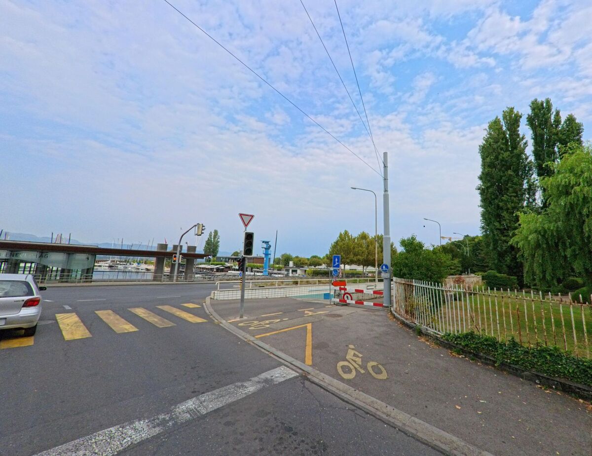 In Cologny (1208, Kanton Genf) führt eine Strasse mit Fussgängerstreifen am Hafenbereich mit Booten und Hafenanlagen vorbei.