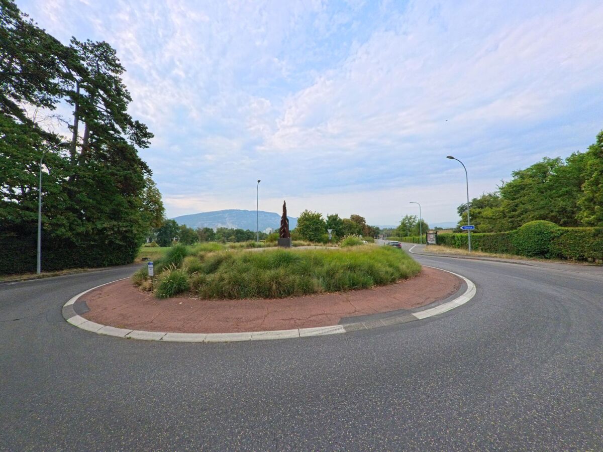 Ein Kreisverkehr in Cologny (1224, Kanton Genf) ist mit Gras bepflanzt und in der Mitte steht eine moderne Skulptur.