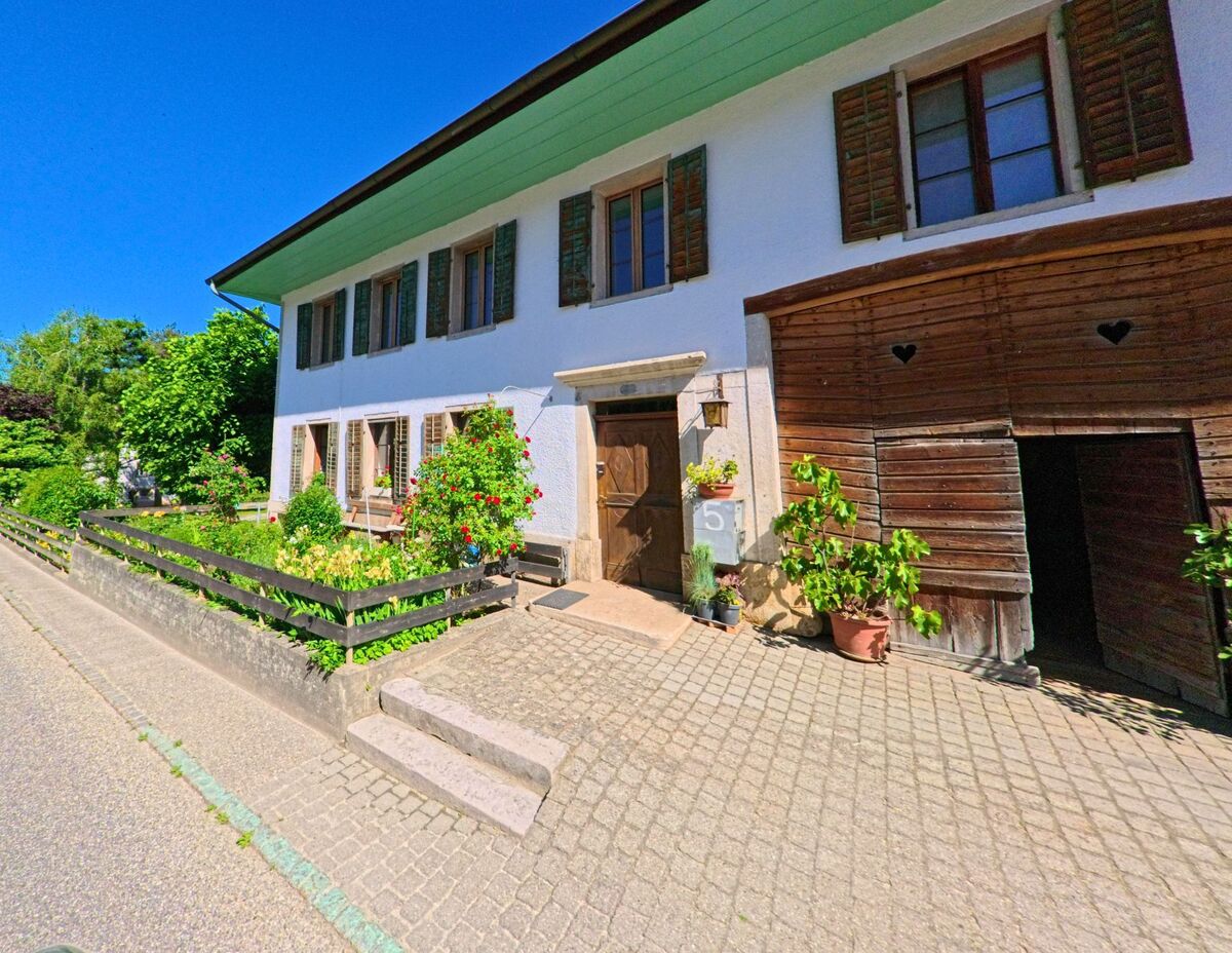 In Crémines (2746, Kanton Bern) steht ein traditionelles Wohnhaus mit gepflegtem Vorgarten und einem angrenzenden Holzschuppen mit herzförmigen Lüftungsausschnitten.