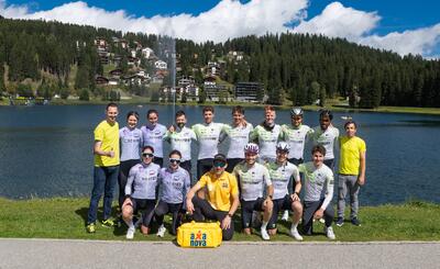 Gruppenfoto von CTO SPORTS in Altstätten 9450, Kanton St. Gallen, Team in Radbekleidung am See mit Bergdorf im Hintergrund, sonnige Stimmung und sportlicher Zusammenhalt.
