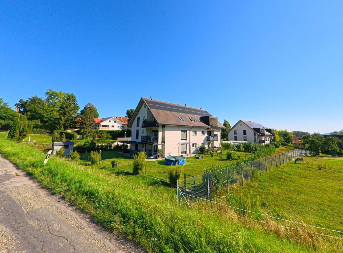 Am Rand von Cudrefin (1588, Kanton Waadt) stehen moderne Mehrfamilienhäuser mit gepflegten Gärten und angrenzenden Wiesen.