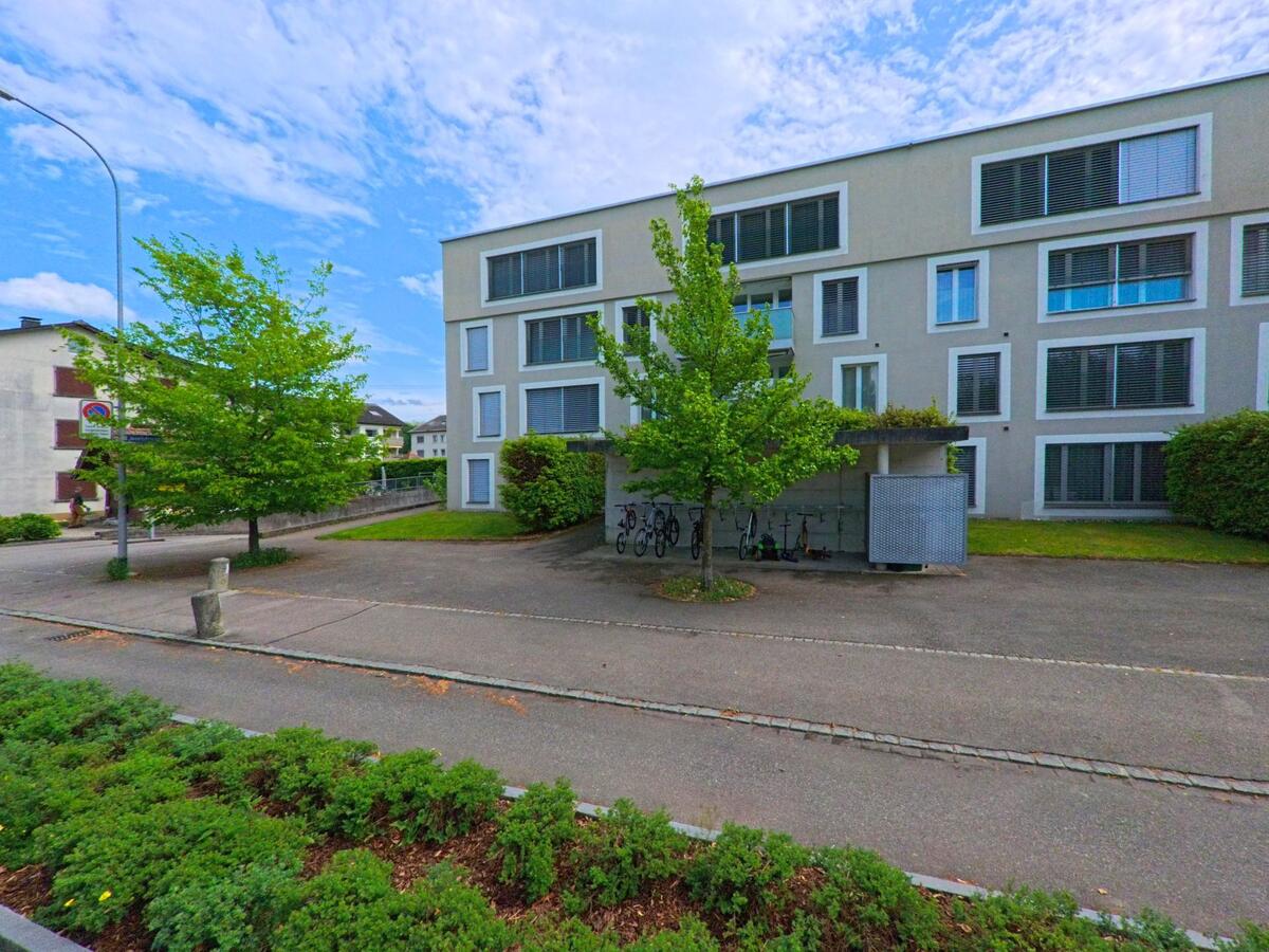  Ein modernes Mehrfamilienhaus mit klarer Architektur und Fahrradunterstand steht in Däniken (4658, Kanton Solothurn) inmitten eines ruhigen Wohnquartiers.