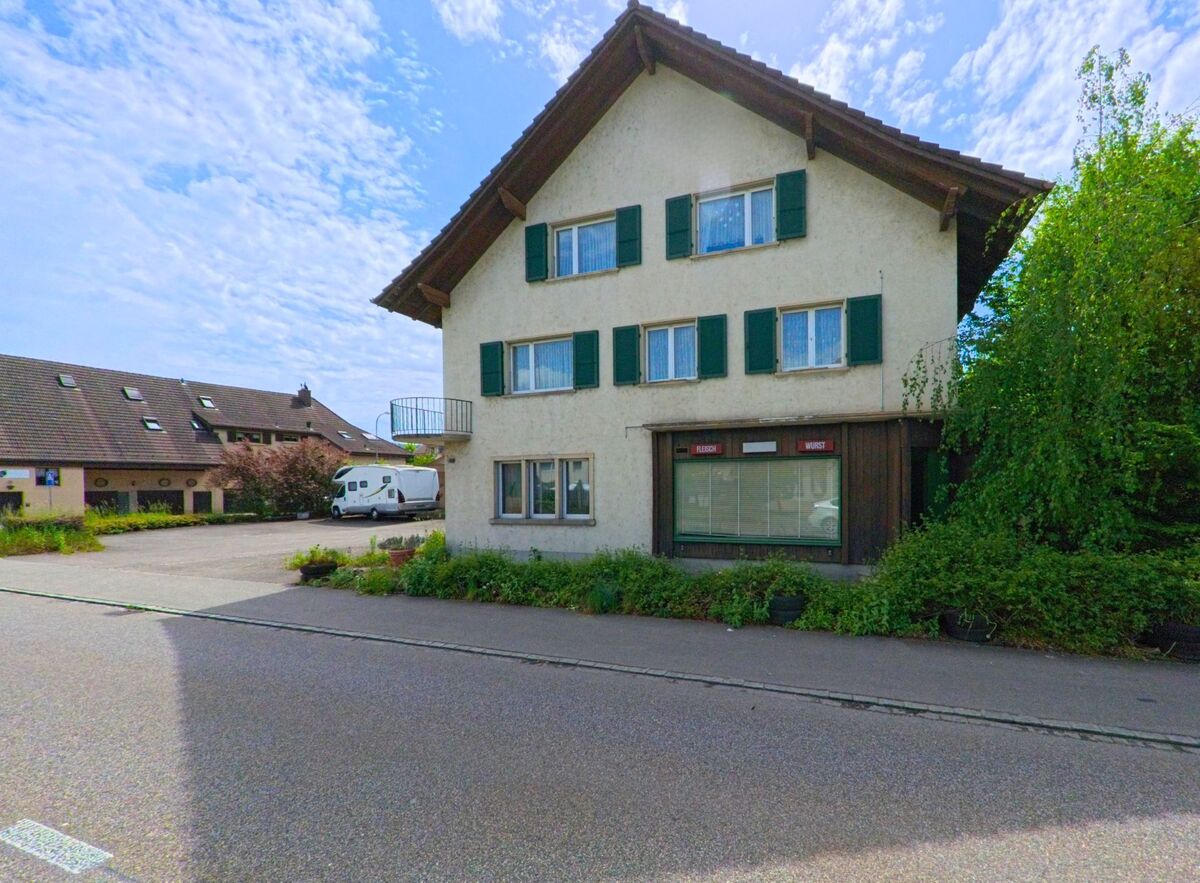 In Däniken (4658, Kanton Solothurn) befindet sich ein älteres Wohnhaus mit grünen Fensterläden und einem kleinen Ladenlokal im Erdgeschoss.