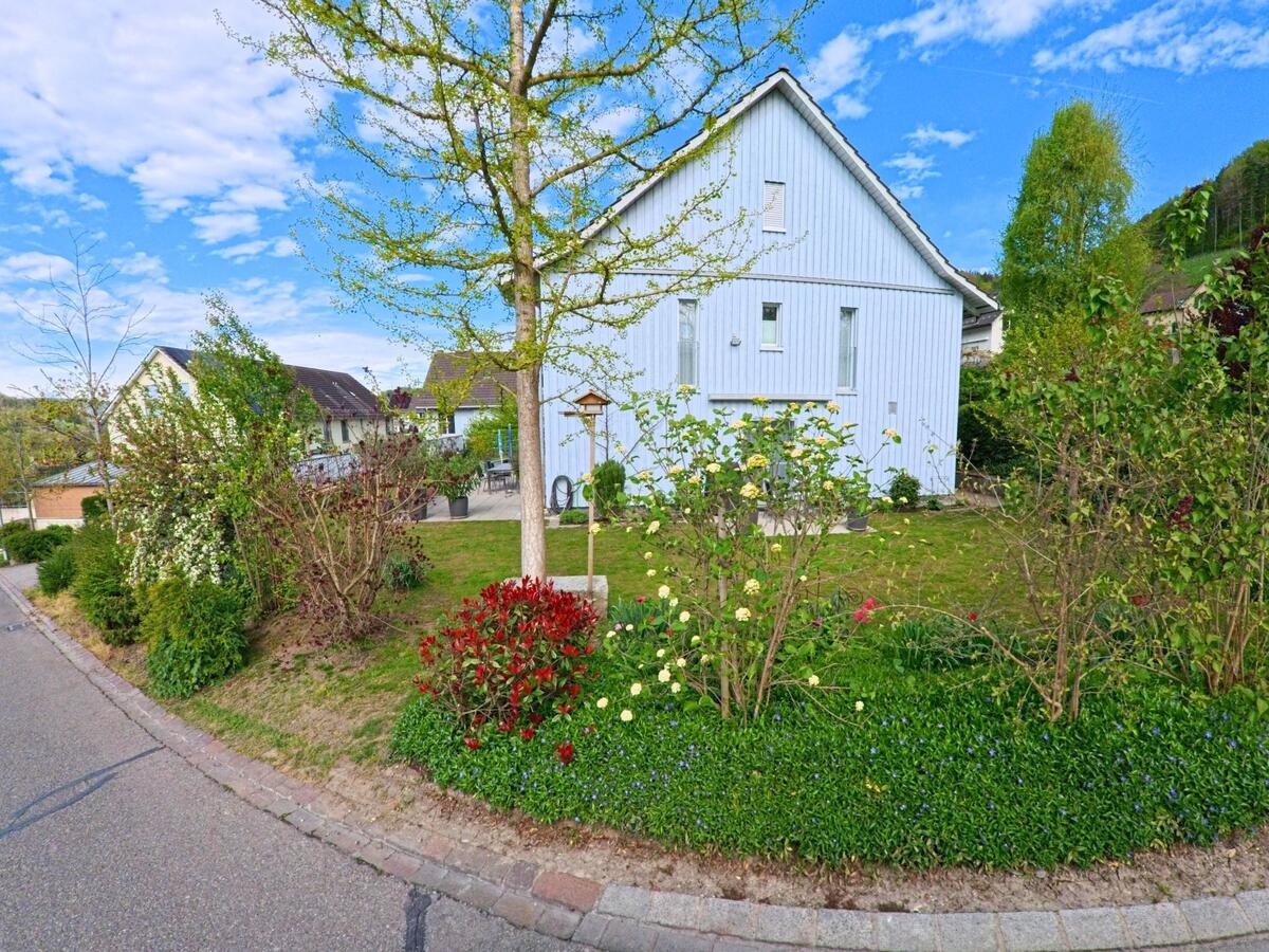 Ein hellblaues Wohnhaus mit gepflegtem Vorgarten und Vogelhaus steht in der Gemeinde Dättlikon im Kanton Zürich, PLZ 8421, an einer ruhigen Anliegerstrasse.